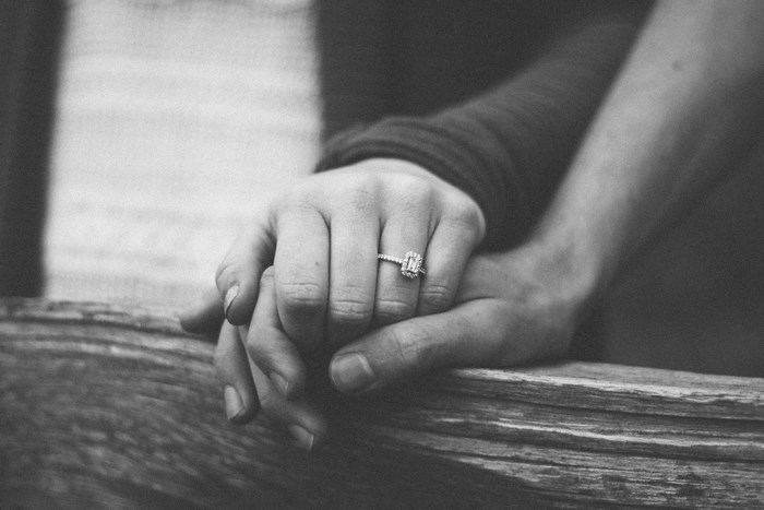Couple holding hands with engagement ring