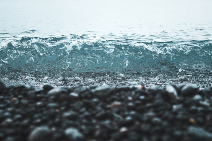 Close-up of a wave crashing on a pebble beach