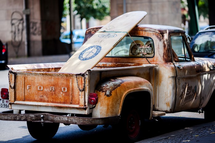 Rusty Ford pickup truck with surfboard