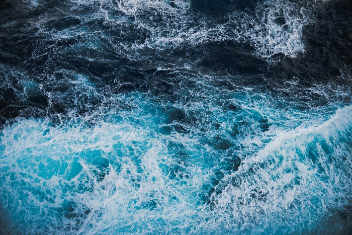 Aerial view of dark blue ocean waves with white foam