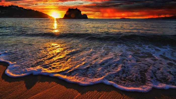Sunset over the ocean with waves on the beach