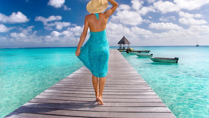 Woman in a blue sarong walks on a wooden pier