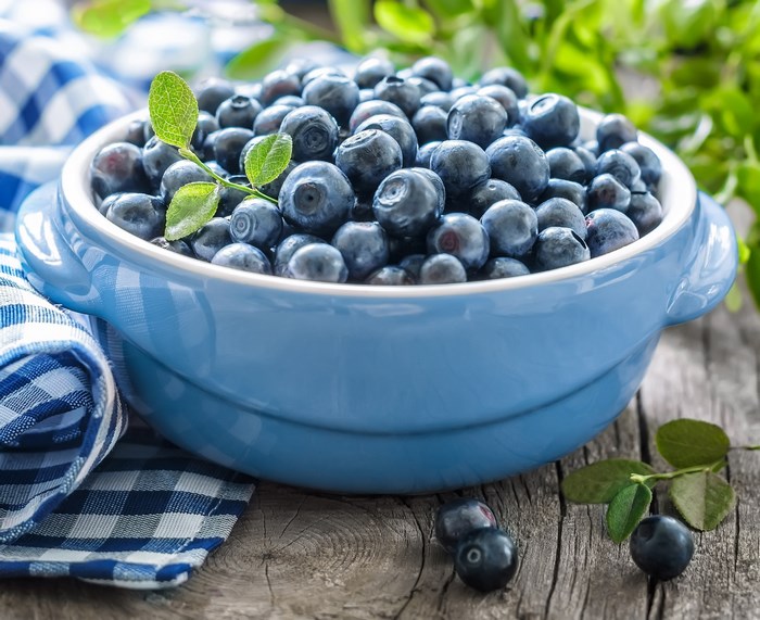 Blueberries in a blue bowl on a wooden table