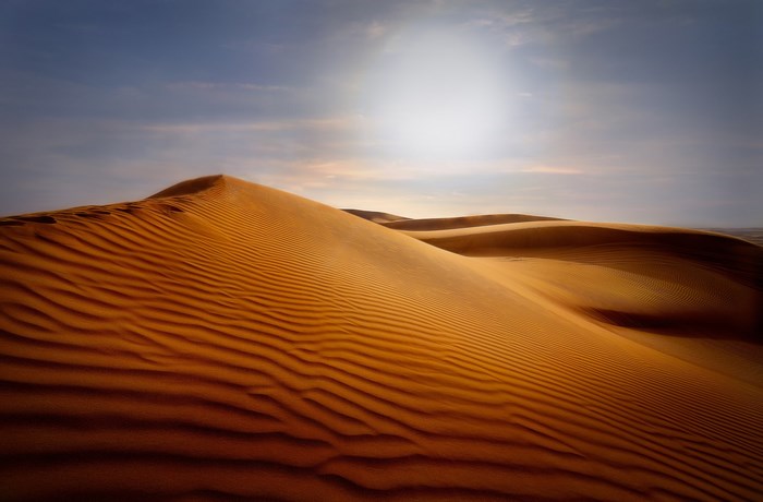 Desert sand dunes under a bright sky