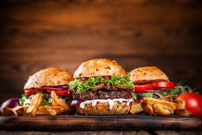 Three Delicious Burgers with Fries on Wooden Board