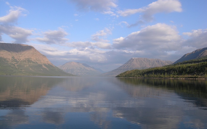 Calm lake reflecting mountains and sky