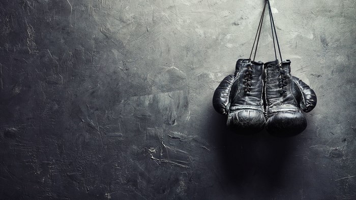 Pair of black boxing gloves hanging on a wall