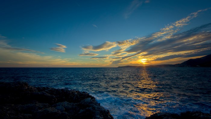 Sunset over the ocean with rocky shore