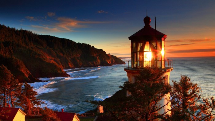Lighthouse on a cliff overlooking the ocean at sunset