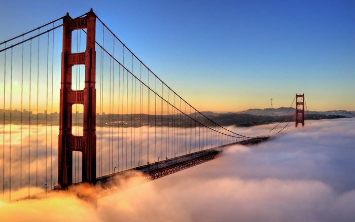 Golden Gate Bridge emerging from fog at sunrise