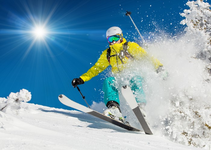 Skier in yellow jacket skiing down a snowy slope