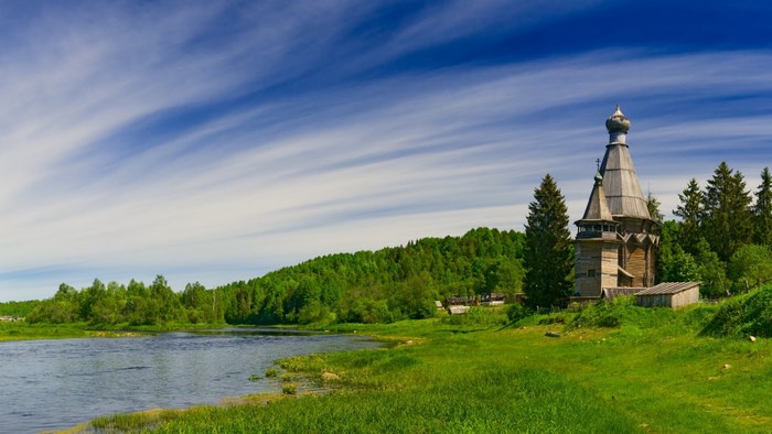 Wooden church by a river in a forest