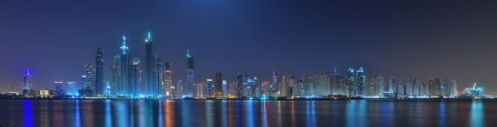 Panoramic night view of Dubai skyline with illuminated skyscrapers