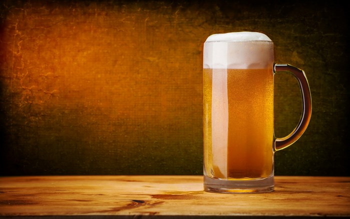 Glass of beer with foam on a wooden table