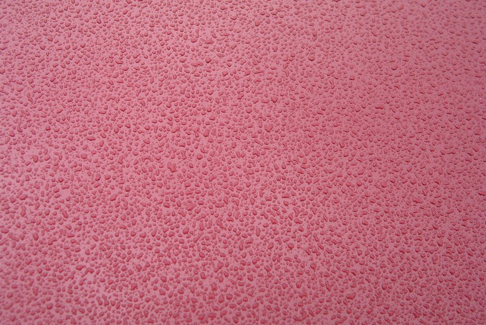 Water drops on a pink surface