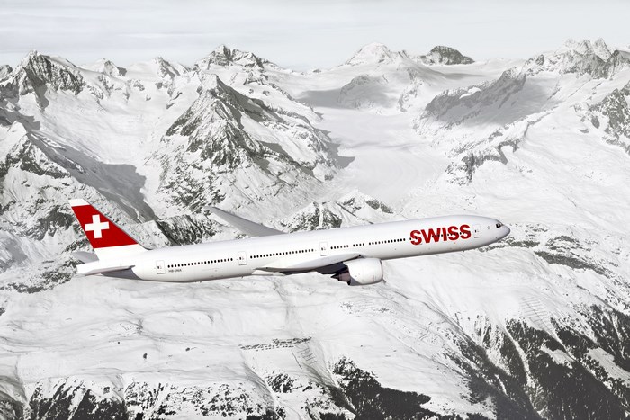Swiss Boeing 777 flying over snowy mountains