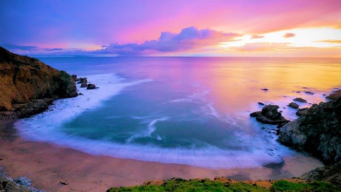 Ocean sunset with colorful sky and rocky shore