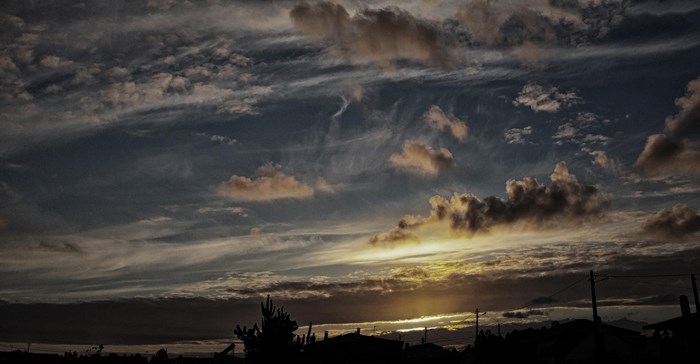 Sunset clouds over silhouetted houses