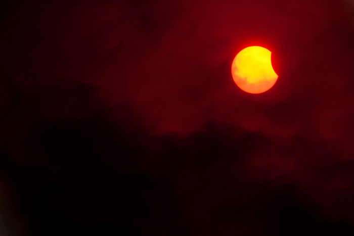 Partial solar eclipse through dark clouds
