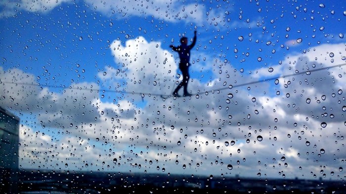 Person on tightrope with rain on window