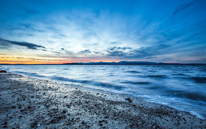 Ocean waves on a pebble beach at sunset