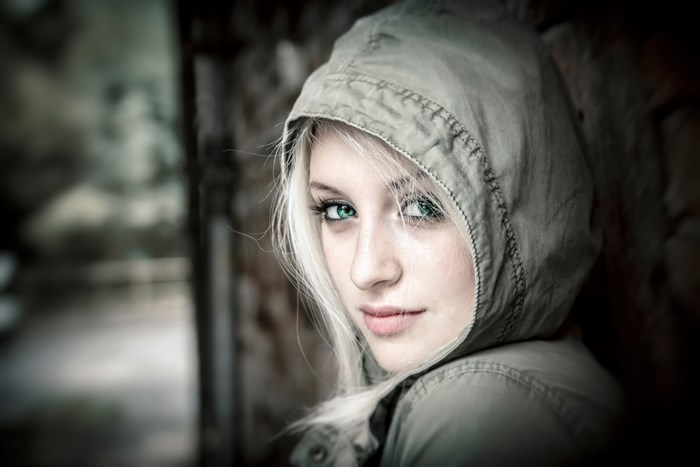 Woman with blonde hair and green eyes wearing a hooded jacket