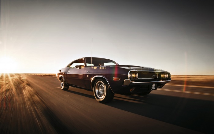 Dodge Challenger driving on a road at sunset