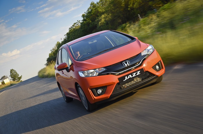 Orange Honda Jazz driving on a road