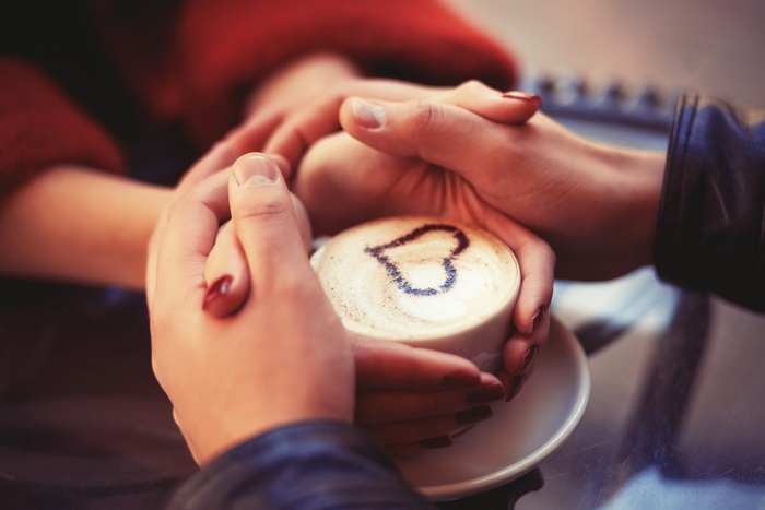 Couple holding coffee cup with heart art