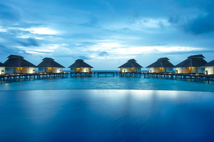Overwater bungalows at dusk with infinity pool