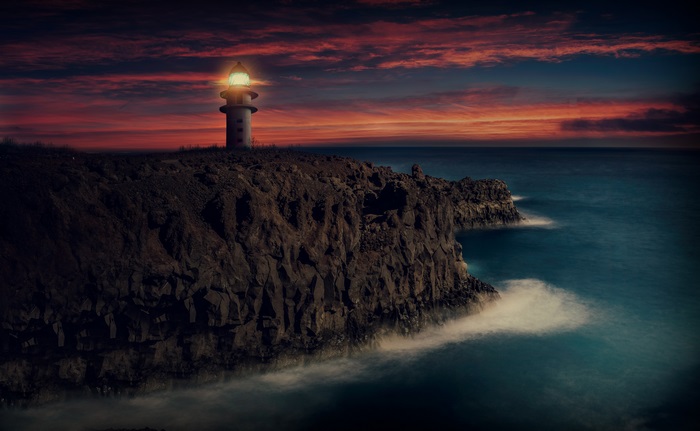 4K Lighthouse on Rocky Cliff at Sunset