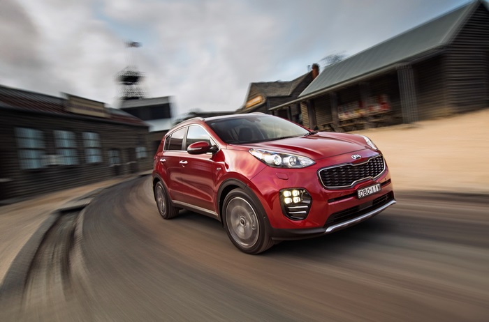 Red Kia Sportage GT Line driving on a road