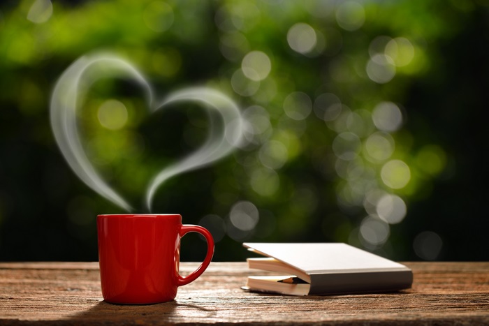 Red coffee mug with heart-shaped steam and book