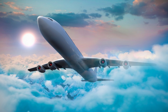 Airplane flying through clouds at sunset