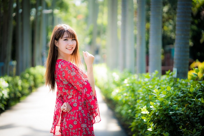 Asian woman in red floral dress in park