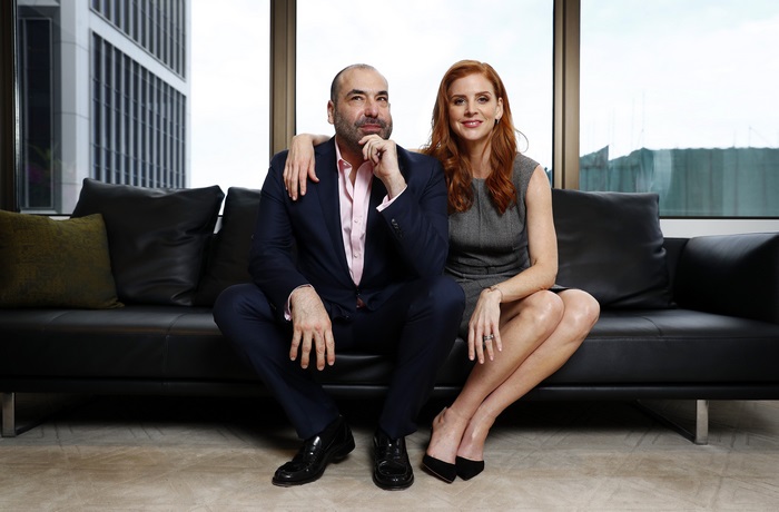 Man and woman in suits sitting on a couch