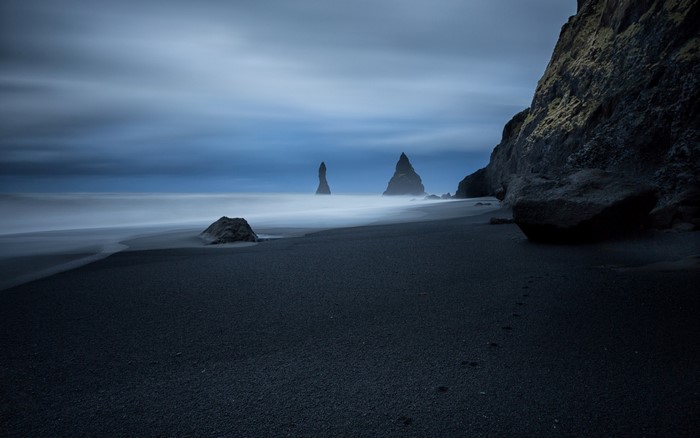 Black sand beach with sea stacks and waves