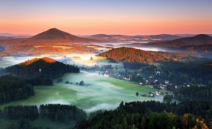 Misty morning landscape with hills and a village in Czech Republic