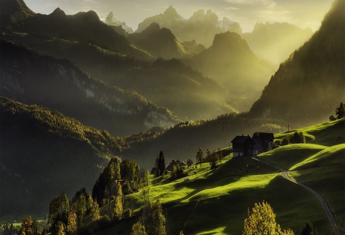 Sunrise over Swiss Alps with cabins and misty mountains