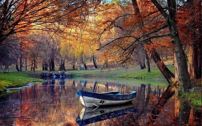 Autumn Park Scene with Boat on Reflective Pond