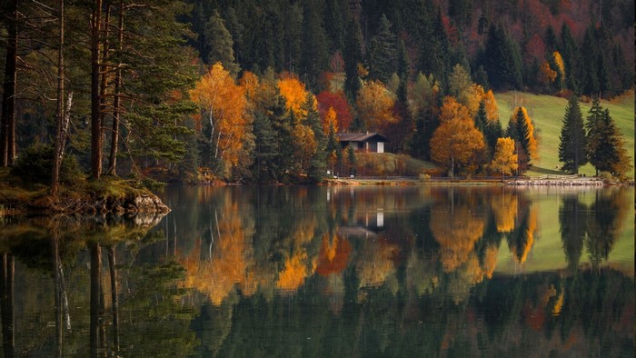Serene Lake with Reflective Autumn Forest and House