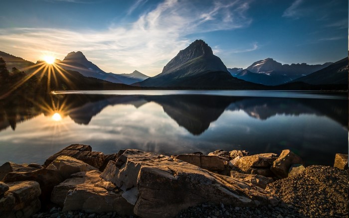 Sunset over a mountain lake with sun rays and reflections