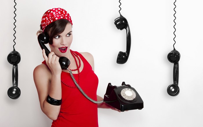 Woman in red dress with vintage telephone and hanging receivers