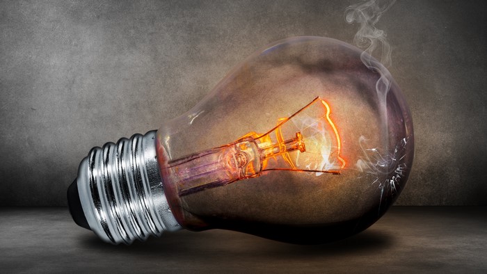 Burning light bulb with smoke and cracks