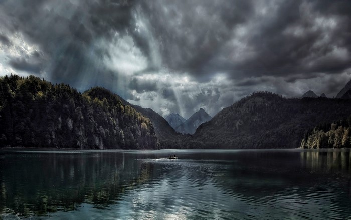 Lake and mountains with dramatic clouds and sun rays
