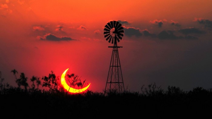 Solar eclipse over Texas with windmill at sunset