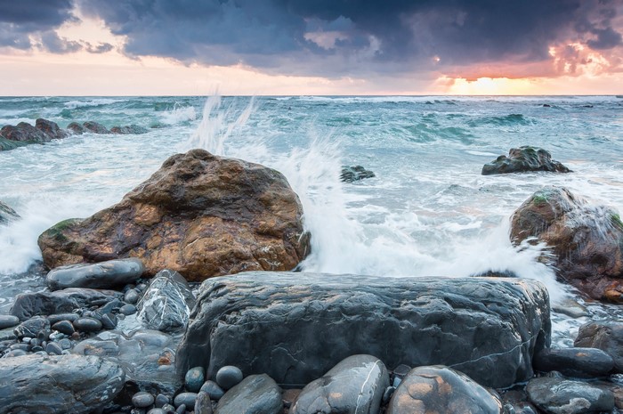 Waves crashing on rocky shore at sunset