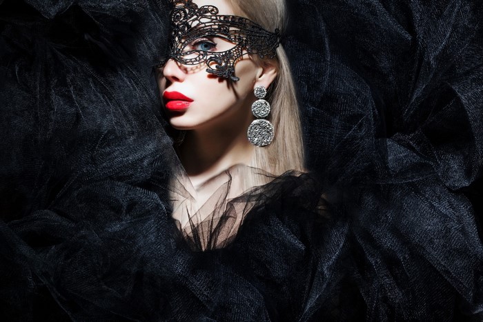 Woman wearing a black lace mask and earrings