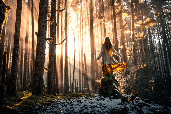 Woman in a forest with sunbeams