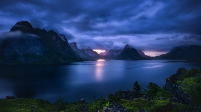 Dark clouds over mountains and lake at sunset